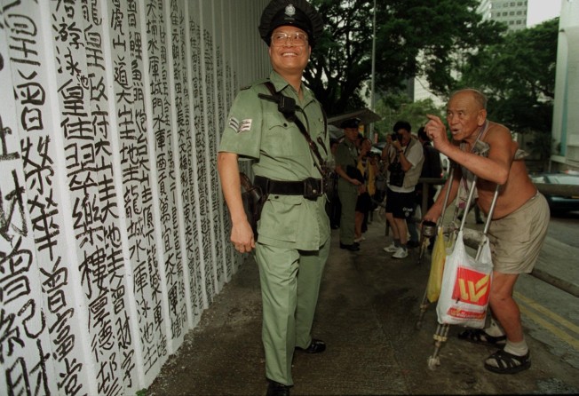 The graffiti artist known as the King of Kowloon, Tsang Tsou-choi, lectures police after being caught writing on the wall near Government House on the day British rule in Hong Kong ended. Photo: SCMP