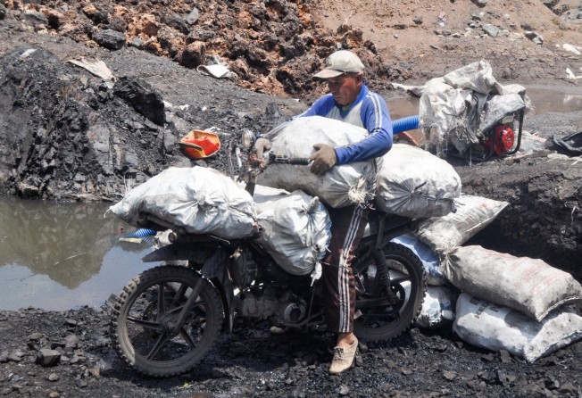 Motorcycle drivers carry bags of coal out of the mine to be loaded onto trucks and sold to factories. Motorcycle drivers can usually carry between 4-6 bags of coal at a time weighing up to 20kg. Photo: Hafidz Trijatnika
