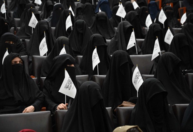 Veiled students hold Taliban flags as they listen to women speakers before a pro-Taliban rally at the Shaheed Rabbani Education University in Kabul. Photo: AFP