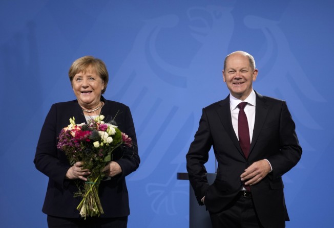 German Chancellor Olaf Scholz and his predecessor Angela Merkel laughs together during a handover ceremony in Berlin on Wednesday. Photo: AP
