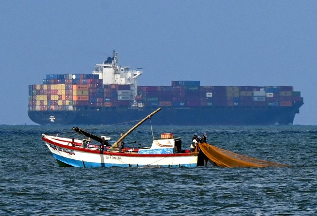 Fishermen cast a net as a cargo ship departs the Colombo International Container Terminal earlier this month. Sri Lanka’s import bills have skyrocketed since last year. Photo: AFP