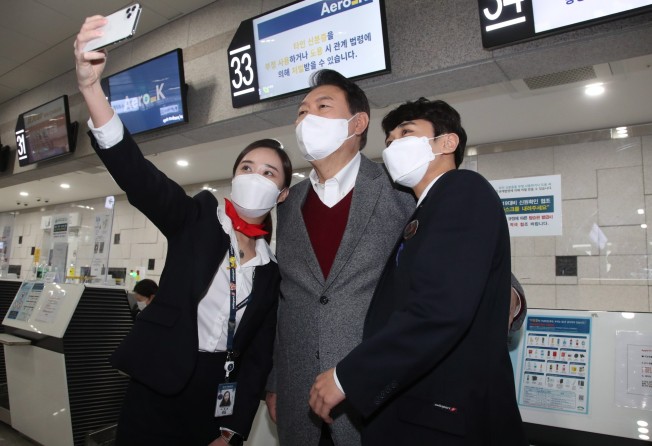 Yoon Suk-yeol, centre, takes a selfie with airport employees during a visit to Cheongju last month. Photo: EPA/Yonhap