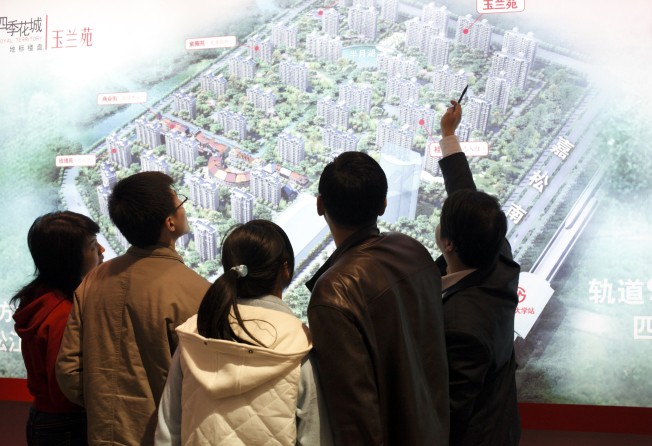 An agent shows potential buyers the layout of a new residential development at a real estate fair in Shanghai on 15 March, 2009. Photo: Corbis via Getty Images