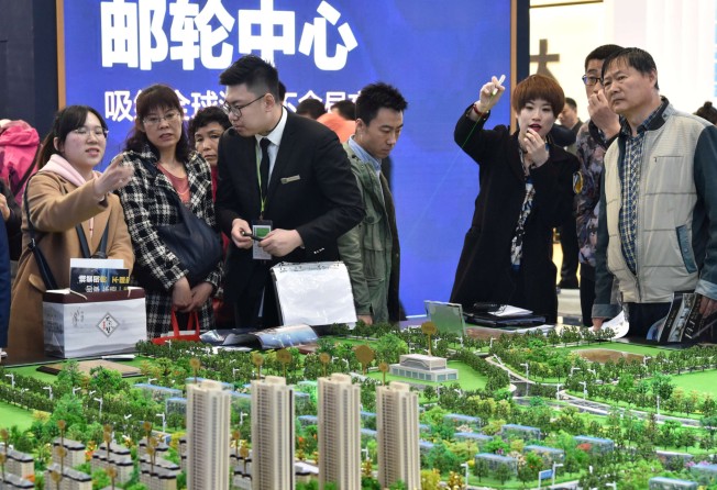 Sales staff introduce models of a residential compound to visitors during Dalian Spring Real Estate Fair in Dalian, Liaoning province on April 12, 2018. Photo: Reuters.