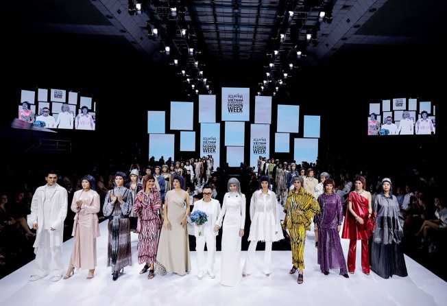 Cong Tri posing with models wearing his designs at the end of a show at Vietnam International Fashion Week in Ho Chi Minh City. Photo: AFP