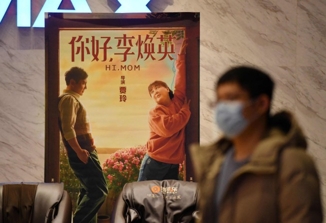 A man walking past a poster for the movie Hi, Mom at a cinema in Beijing, in February 2021. Photo: AFP