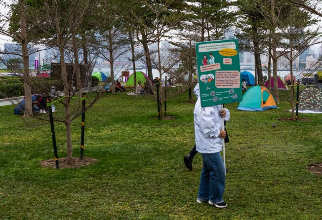 A Labour Department officer holds a banner encouraging the public to take the Covid-19 vaccine at Tamar Park in Hong Kong on Sunday. Photo: Bloomberg