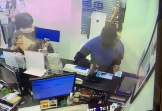 A screengrab showing the robber pointing the gun-like object at the bank teller. Photo: Handout