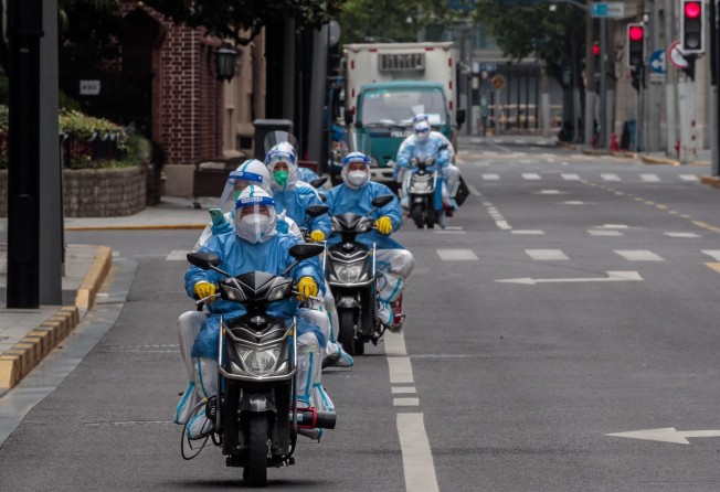 Medical personnel in protective gear rode scooters through Nanjing street in Shanghai on April 25, 2022. Photo: EPA-EFE