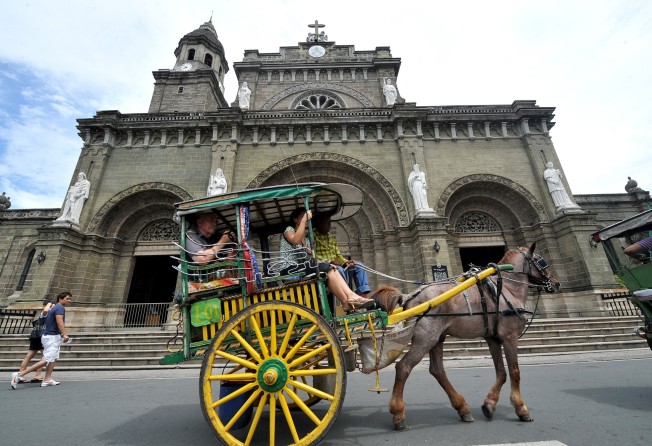 Tourists pass the Manila Cathedral in Intramuros in Manila. Photo: AFP