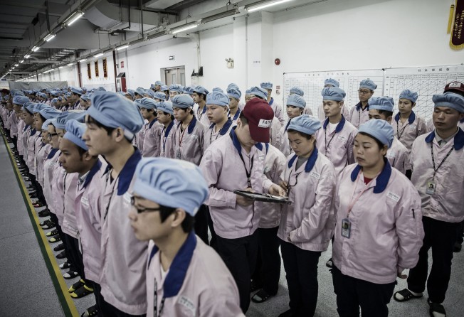 A supervisor holds an iPad as he checks an employee’s badge during roll-call at Apple supplier Pegatron Corp’s factory in Shanghai on April 15, 2016. Photo: Bloomberg