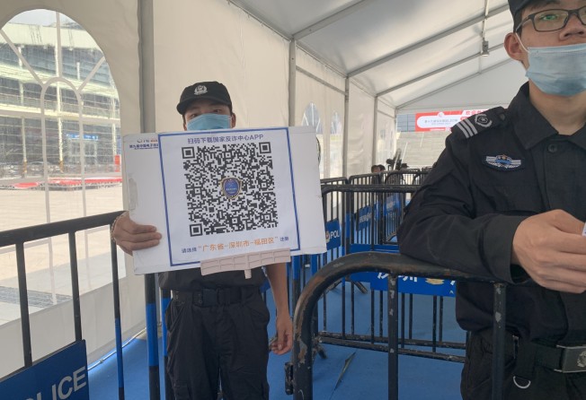 A guard presents the QR code for installing an anti-fraud app before entering an exhibition centre in Shenzhen. Photo: Yujie Xue