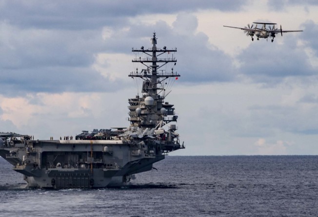 An early-warning aircraft flies past the aircraft carrier USS Ronald Regan during a US Navy drill in the South China Sea on July 6, 2020. Photo: EPA-EFE/MC3 Cody Beam