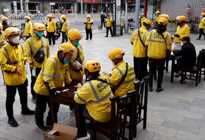 Meituan delivery workers hold antigen testing kits as they line up to get tested for the coronavirus in Beijing, China on May 9. Photo: Reuters