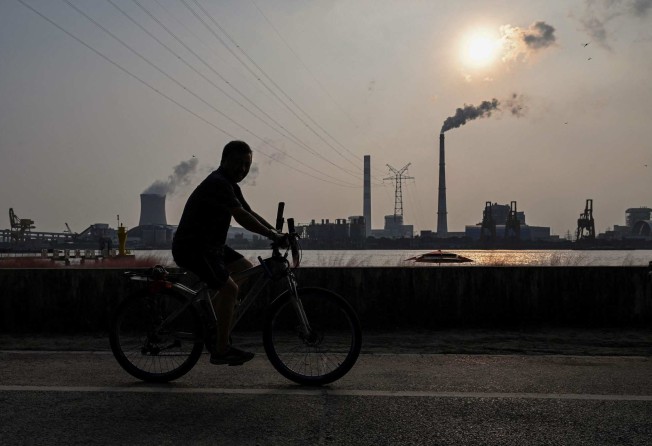 A man rides a bicycle on a promenade along the Huangpu river across from the Wujing Coal-Electricity Power Station in Shanghai on September 28, 2021. Photo: AFP