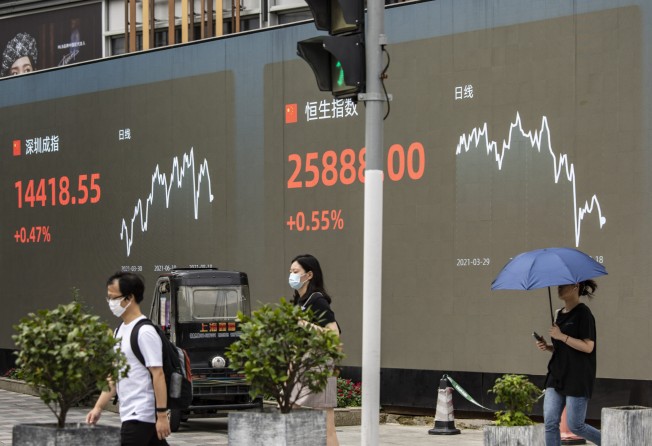 Pedestrians walk past a screen displaying the Shenzhen Stock Exchange and the Hang Seng Index figures in Shanghai. Photo: Bloomberg