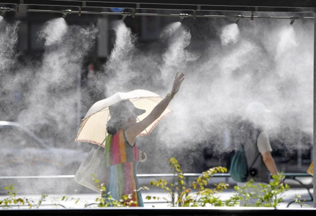 People walk under mist showers on a sweltering day in Tokyo on August 1. Officials called on the public to remain hydrated and take precautions against heatstroke, and to keep an eye on elderly neighbours. Photo: Kyodo