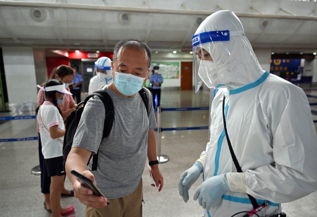 A tourist shows an airport worker his Hainan health code in Sanya on Tuesday. Photo: Xinhua