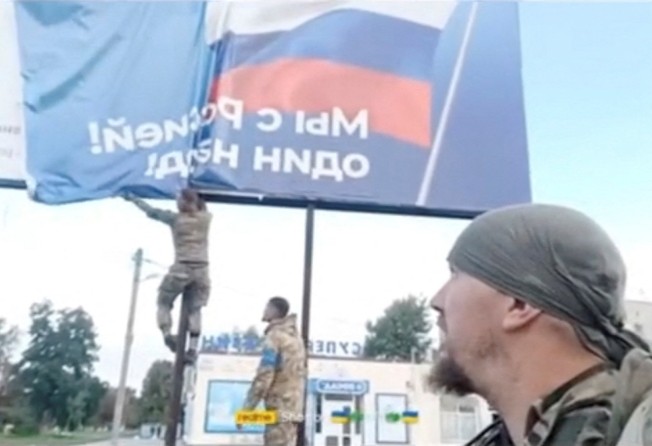 Ukrainian troops pull down a Russian poster off a billboard in Balakliya, Kharkiv region, Ukraine. Photo: Reuters