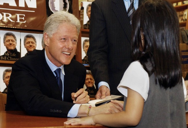Former US president Bill Clinton shakes hands with a girl during an autograph session for his new book, My Life, in 2004, at the Hue-Man bookstore in New York. Photo: AFP