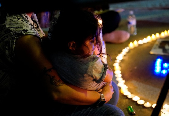 A woman in California cradles her daughter at a candlelit vigil protesting at the death of Mahsa Amini. Photo: Reuters