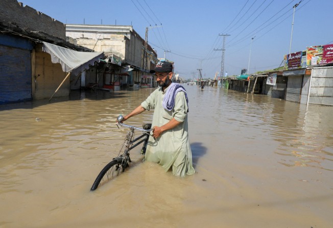 A man walks with a bicycle in floodwater following rains and floods in Nowshera, Pakistan on August 29. Photo: Reuters