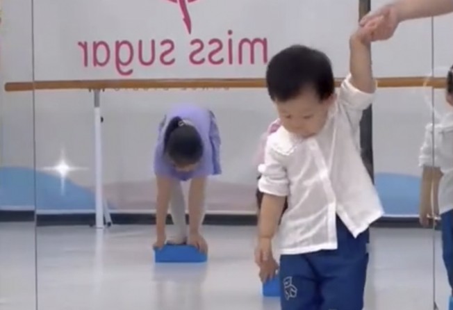 The little girl stands on a yoga block to learn how to dance. Photo: Baidu
