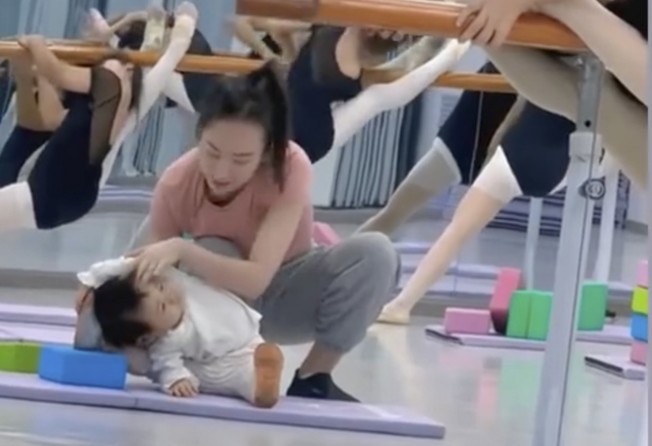 The mother adjusts her daughter’s position during a stretch. Photo: Baidu