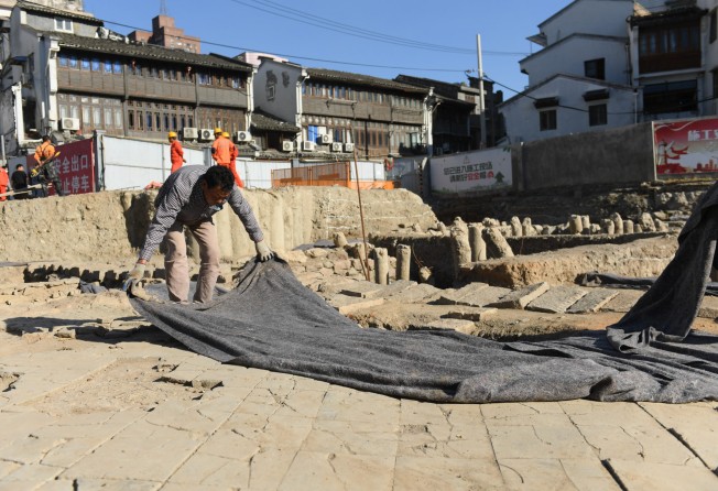 A worker covers a portion of the archaeological dig . Photo: Xinhua