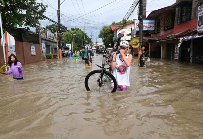 Residents wade through a flooded street in Kawit town, Cavite province on Sunday, a day after Tropical Storm Nalgae hit. Photo: AFP