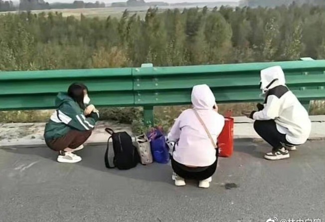 People are seen resting on the side of a road after fleeing from Foxconn Technology Group’s Covid-19-hit compound in the central Chinese city of Zhengzhou. Photo: Weibo