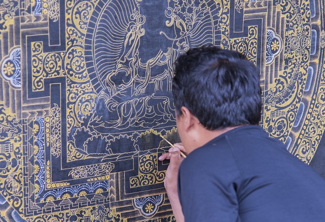 A craftsman paints a Buddhist mandala in a village along the Trans Bhutan Trail. Photo: Tim Pile