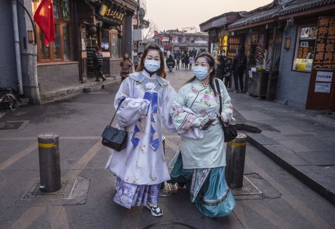 Women wear protective masks and traditional Chinese clothing in Houhai, Beijing, in February last year. Photo: Getty Images