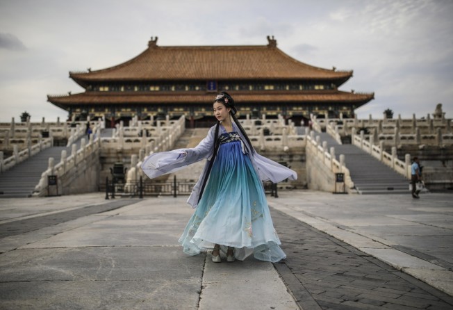 A woman wearing traditional Chinese clothing dances while posing for photographs in the Forbidden City in Beijing in August 2020. Photo: EPA-EFE