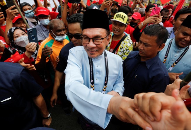 Malaysia’s opposition leader Anwar Ibrahim shakes hands with supporters after filing his nomination to contest the general election. Photo: Reuters