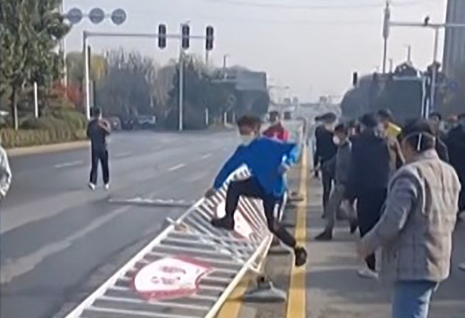Workers at Foxconn Technology Group’s manufacturing complex in Zhengzhou, capital of central Henan province, are seen kicking down barriers in protest, as they clash with security personnel and local police on November 23, 2022. Photo: Agence France-Presse.