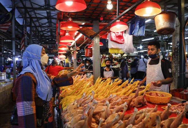 A vendor talks to his customer at wet market in Kuala Lumpur. Malaysia’s economy is set to expand at a slower pace in 2023. Photo: EPA-EFE