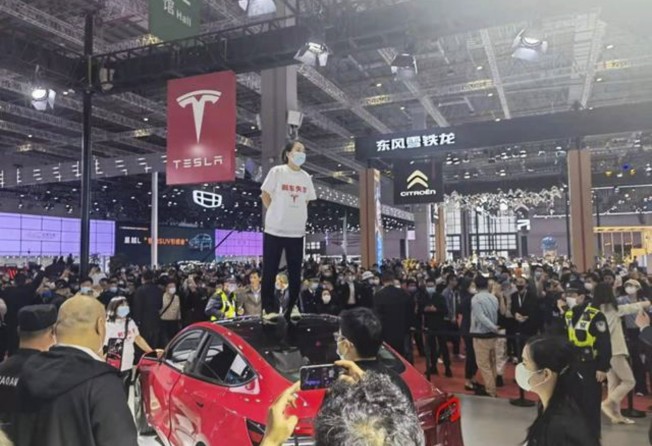 A woman stands on a Tesla at the Shanghai Auto Show in April 2021 to draw the attention of the carmaker for a malfunctioning brake that caused her to crash her Model 3 car. Photo: Baidu