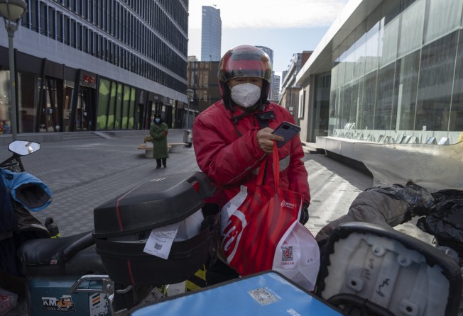 A delivery man carries orders to his bike in Beijing. Photo: AP Photo