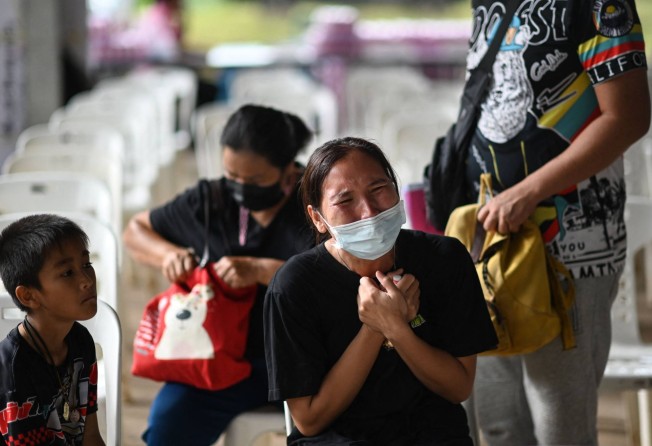 A child sits next to the mother of a victim as she cries outside the nursery, where a former police officer killed 36 people in a mass shooting, in Thailand’s northeastern Nong Bua Lam Phu province in October 2022. Photo: AFP