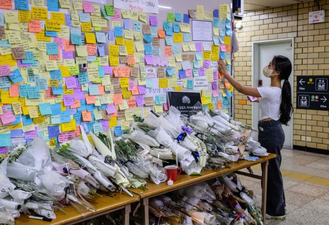 A woman pays her respects as she displays a handwritten note near the entrance to a female toilet at Sindang station in Seoul in September 2022, after a female subway worker was killed by her stalker. Photo: AFP