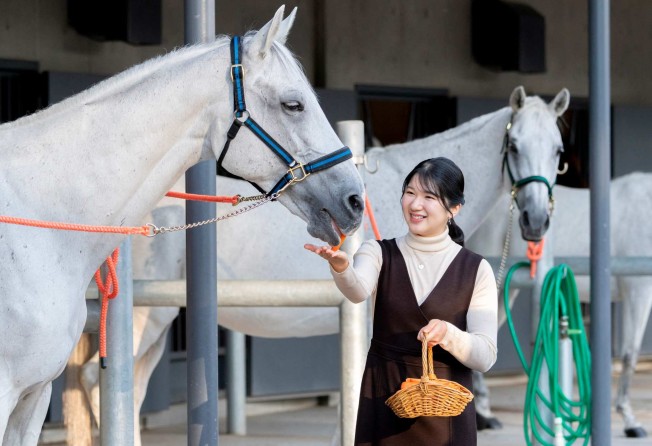 Japan’s Princess Aiko feeding a horse at the Imperial Household Agency’s stables in Tokyo. Photo: Imperial Household Agency/AFP