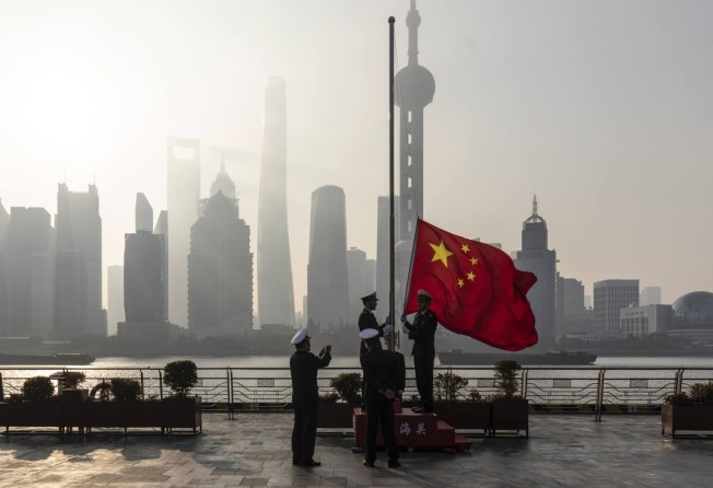 Officials raise a Chinese flag along the Bund in Shanghai. China is doing away with its strict zero-Covid policy after three years of lockdowns, compulsory mass testing, centralised quarantines and contract tracing. Photo: Bloomberg