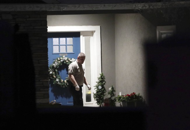 A law enforcement official near the front door of the home where the family members were found dead. Photo: AP