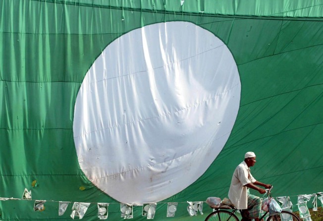 A man cycles past a giant flag of Malaysia’s opposition PAS in the northern state of Kedah. Photo: AFP