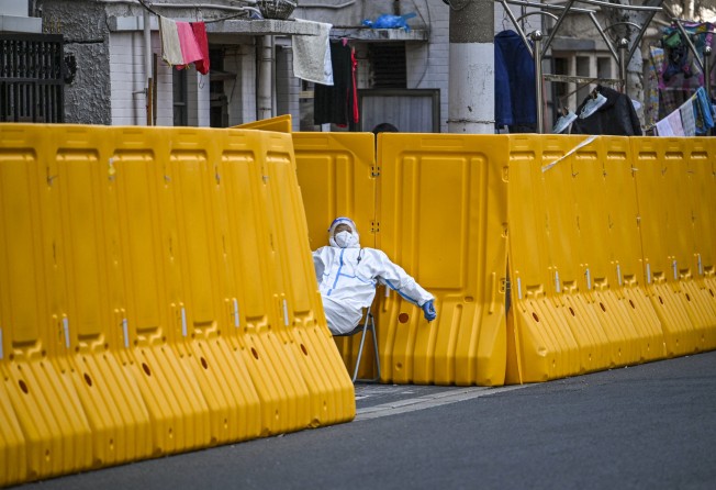A worker in protective gear guards the entrance to a locked down neighbourhood in Shanghai in March last year. Photo: AFP