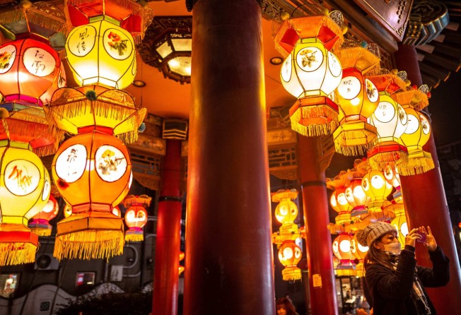 A woman takes pictures next to lanterns in the Chinatown section of Yokohama in Japan, ahead of the Lunar New Year. Photo: AFP