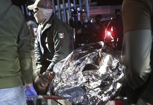 Paramedics carry a migrant who was wounded the deadly fire. Photo: AP