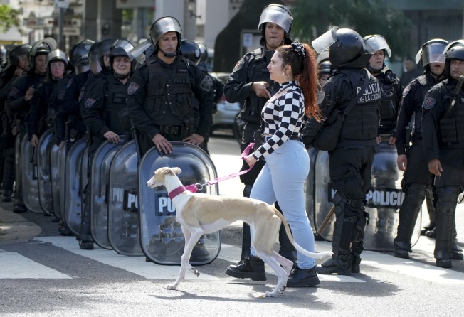 A woman walks her dog past police after they dispersed an anti-government protest in Buenos Aires, Argentina, on April 10. Photo: AP
