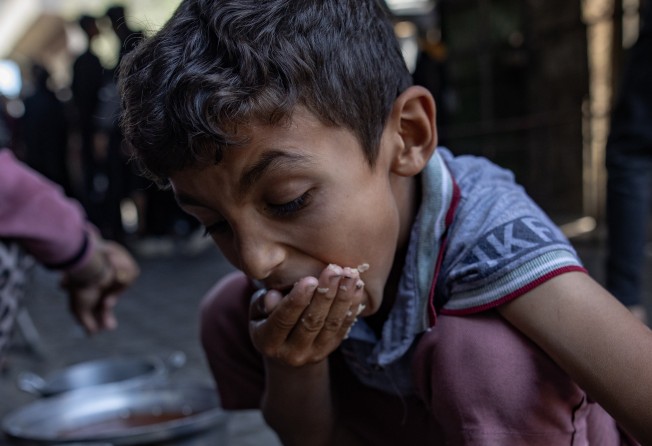 A child eats as displaced Palestinians gather to receive limited food rations in Gaza City on Wednesday. Photo: EPA-EFE